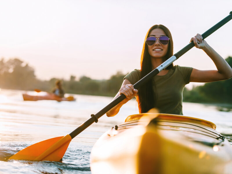 Nice day on kayak. Beautiful young smiling woman kayaking on river